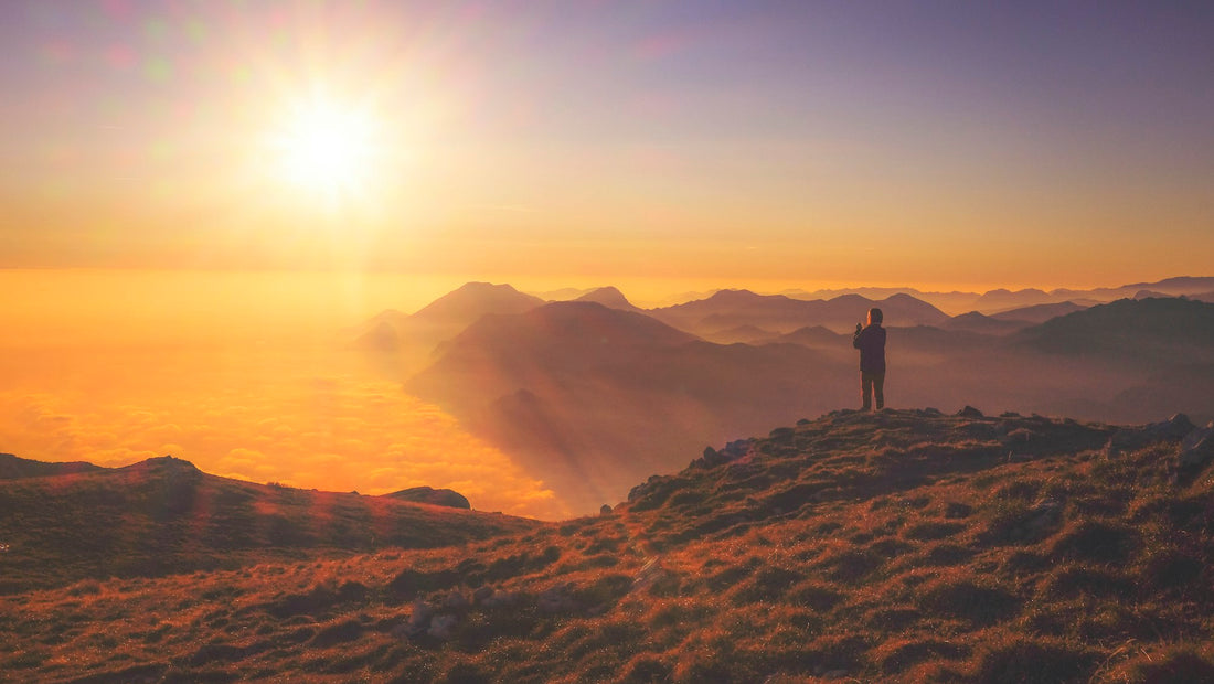Person auf einem Berggipfel im Morgenlicht