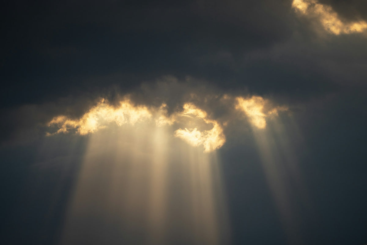 Sonnenstrahlen brechen durch dunkle Wolken