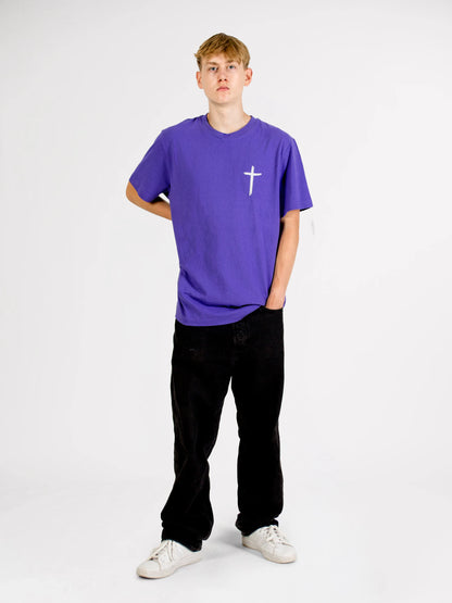 Ganzkörper-Frontansicht eines Models im violetten Source Mode Fearless T-Shirt mit weißem Kreuz Print auf der Brust. Christliche Streetwear als Symbol für Jesus, Glaube, Mut, Stärke und Gottes Gegenwart.