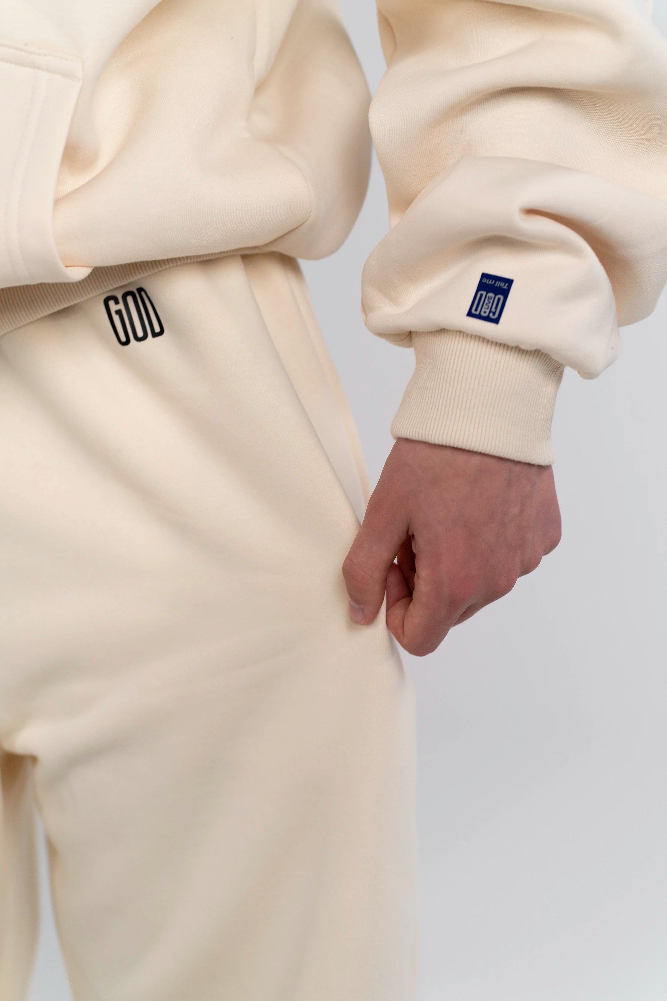 Detailaufnahme des GOD Logo Prints auf der Open Source Signal Fluff Pants von Source Mode. Weiches Heavyweight Material, Relaxed Fit und hochwertiger Print als Symbol für Führung, Gegenwart und Verbindung.