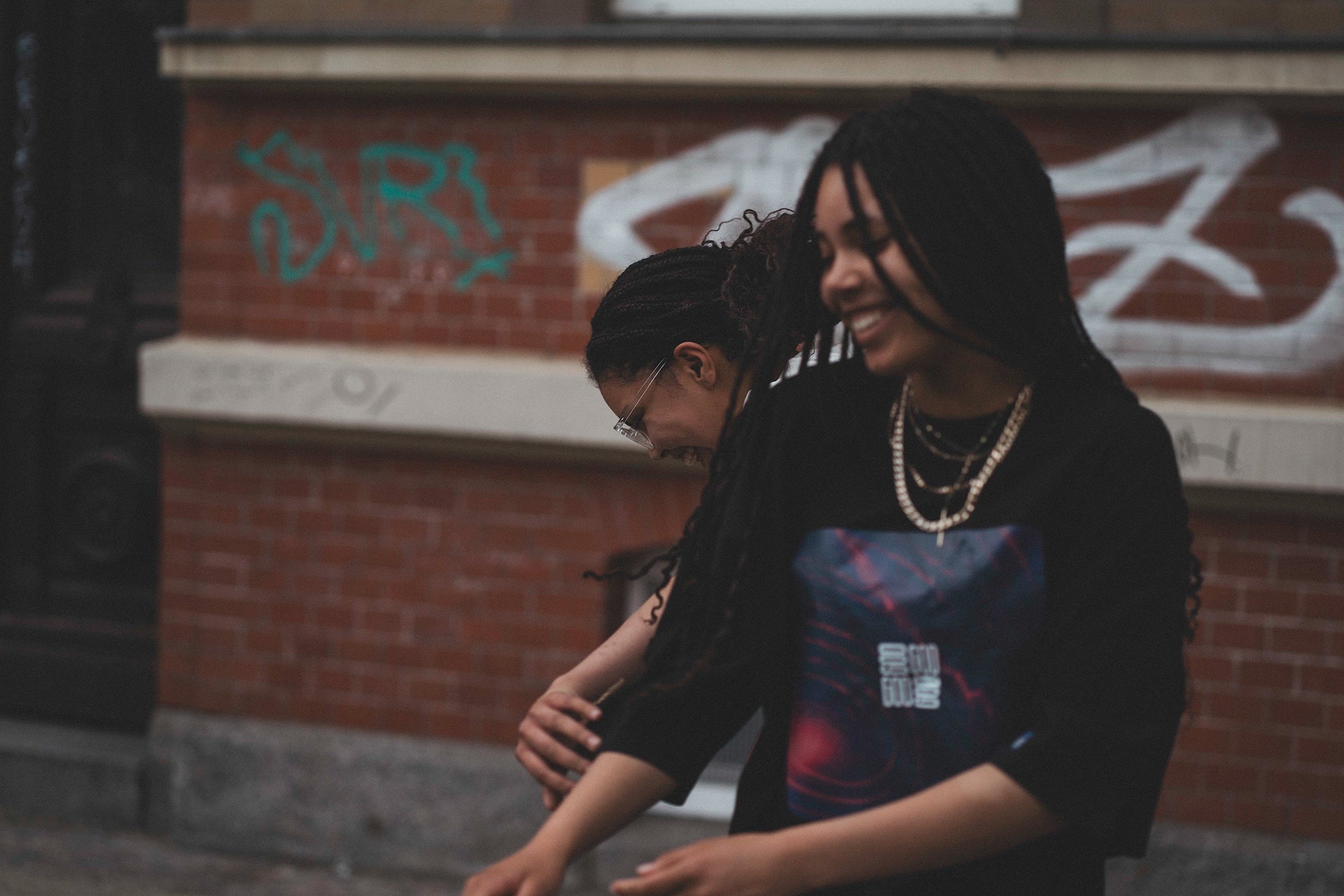 Source Mode – GOD Real Life Streetwear Label Interface. Zwei junge Menschen in Source Mode Streetwear lachen gemeinsam als Ausdruck von echter Gemeinschaft, Schutz, Hoffnung und menschlicher Verbindung. Missionsbild der About-Us-Seite für christliche Premium Streetwear und die Vision, Menschen zu schützen, wahre Beziehungen zu fördern und einen echten Beitrag für die Welt zu leisten. Real Life Label, Human Connection, Community, Innovation, Love, Presence und Future of Humanity. LinkedIn, About Us, Mission,