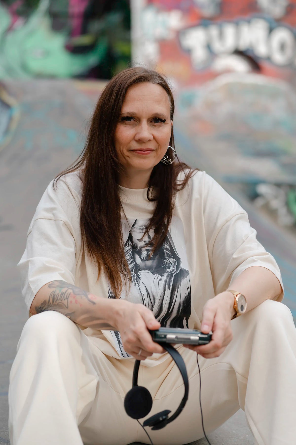 Lifestyle: model in the Open Source Christ-before-Me Boxy Shirt in Natural Raw in front of a graffiti wall