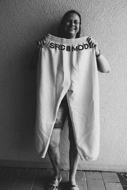 Open Source Signal Cozy Pants in White Sand in der Hand gehalten – Rückenansicht mit SRCMODE-Bund
